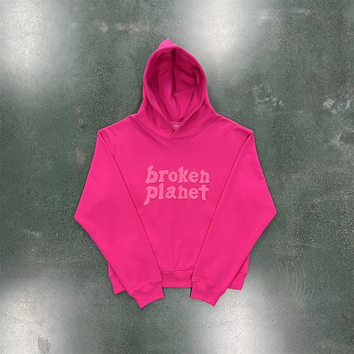 A bright pink Maramalive™ Letter Foam Printed Hoodie Punk Rock Casual Sweater with the text "broken planet" written in a light pink, stylized font on the front. Made from polyester, this street hipster hoodie is laid flat on a concrete floor.