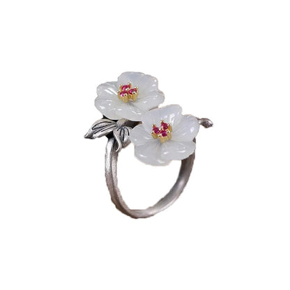 A Fashion Antique Flower Women's Ring by Maramalive™ with two white jade flowers on top of a wooden table.