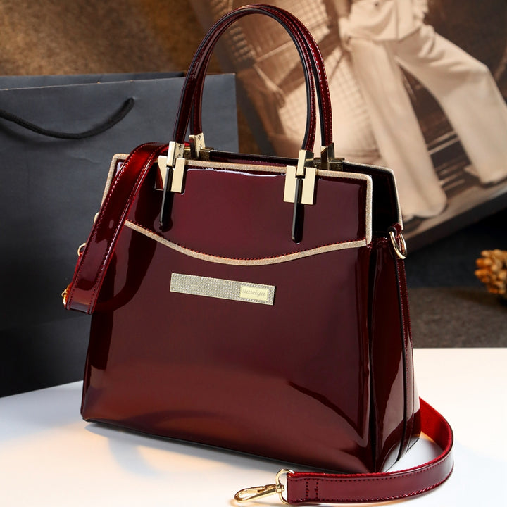 A burgundy patent leather shoulder messenger bag with gold hardware, brand name Maramalive™.
