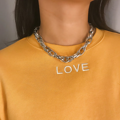 A woman wearing a yellow sweatshirt with the Maramalive™ Heavy metal chain punk retro wild short necklace on it.