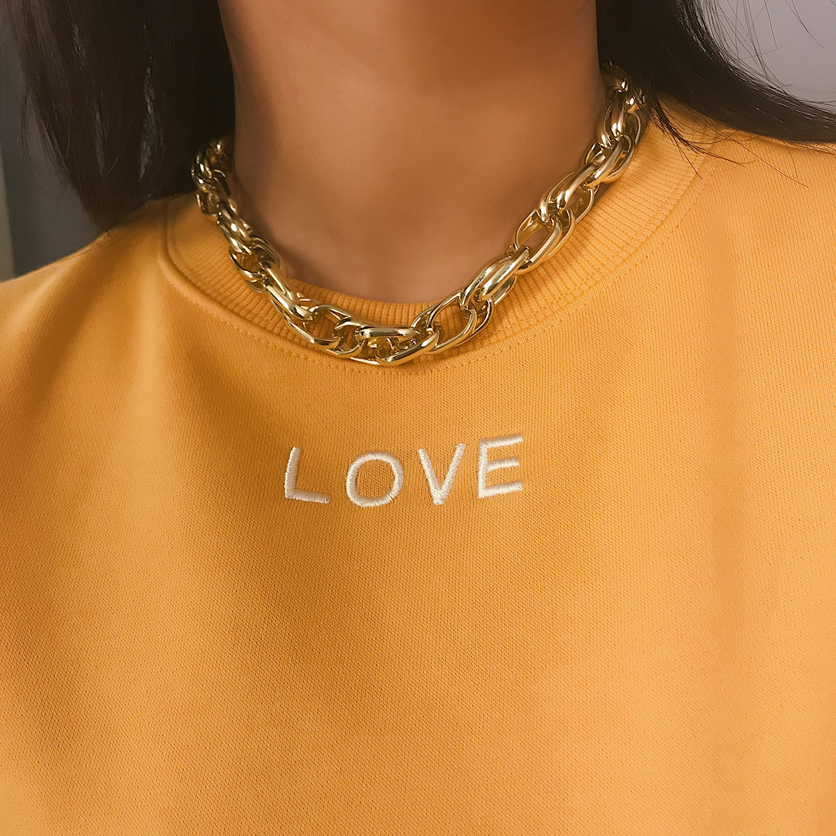 A woman wearing a yellow sweatshirt with the Maramalive™ Heavy metal chain punk retro wild short necklace on it.