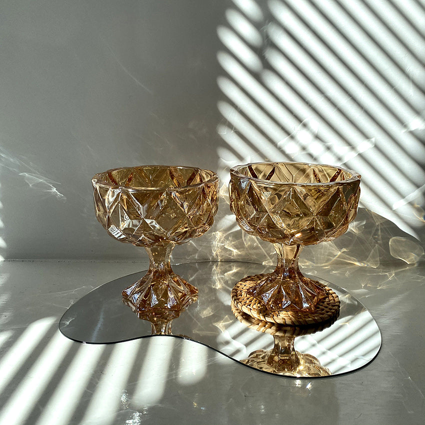 A person holding up a Maramalive™ Amber Crystal Glass bowl in the sun.